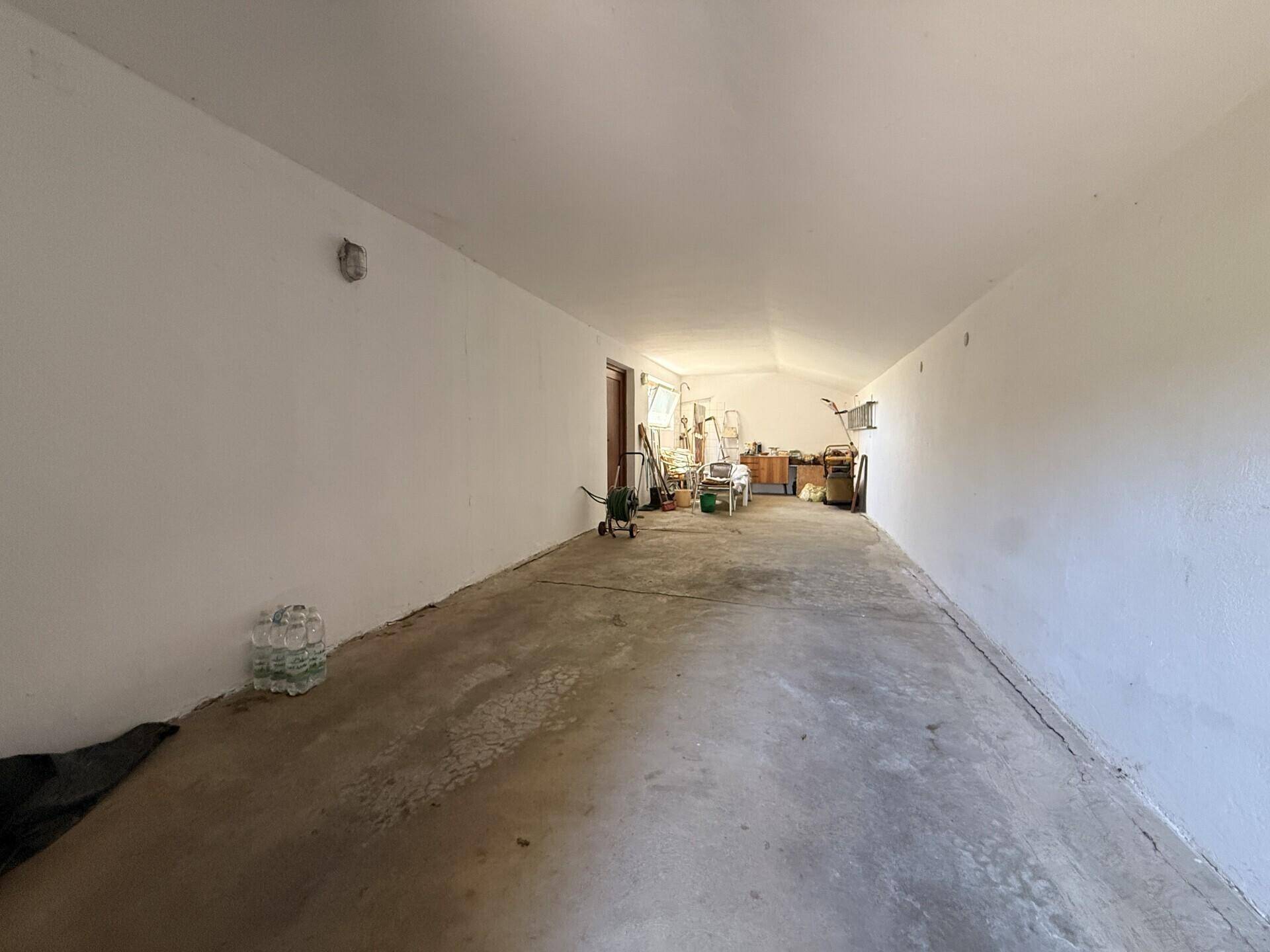 Lange Garage oder Abstellraum mit Betonboden und viel Platz für Fahrzeuge oder Lagerung.