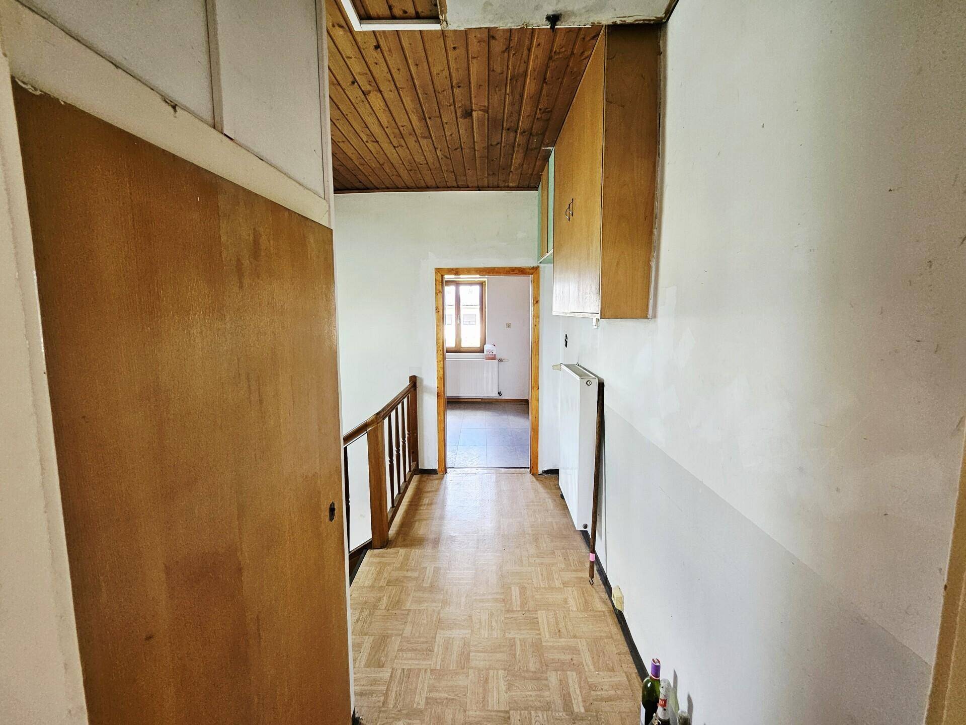 Flur mit Holzdecke und Parkettboden, der zu weiteren Zimmern führt.