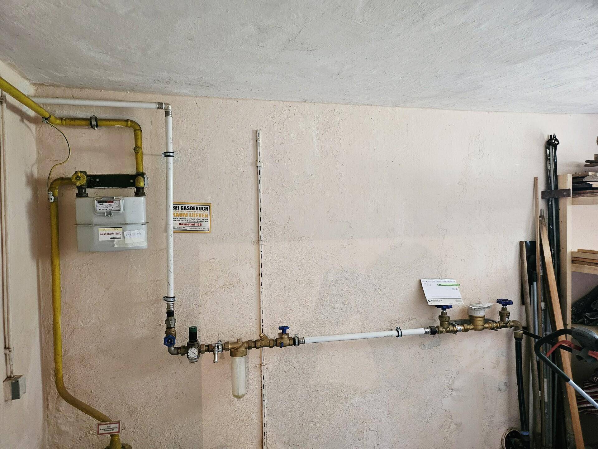 Gaszähler und Rohrleitungen an der Wand eines Technikraums, ordentlich installiert und zugänglich.