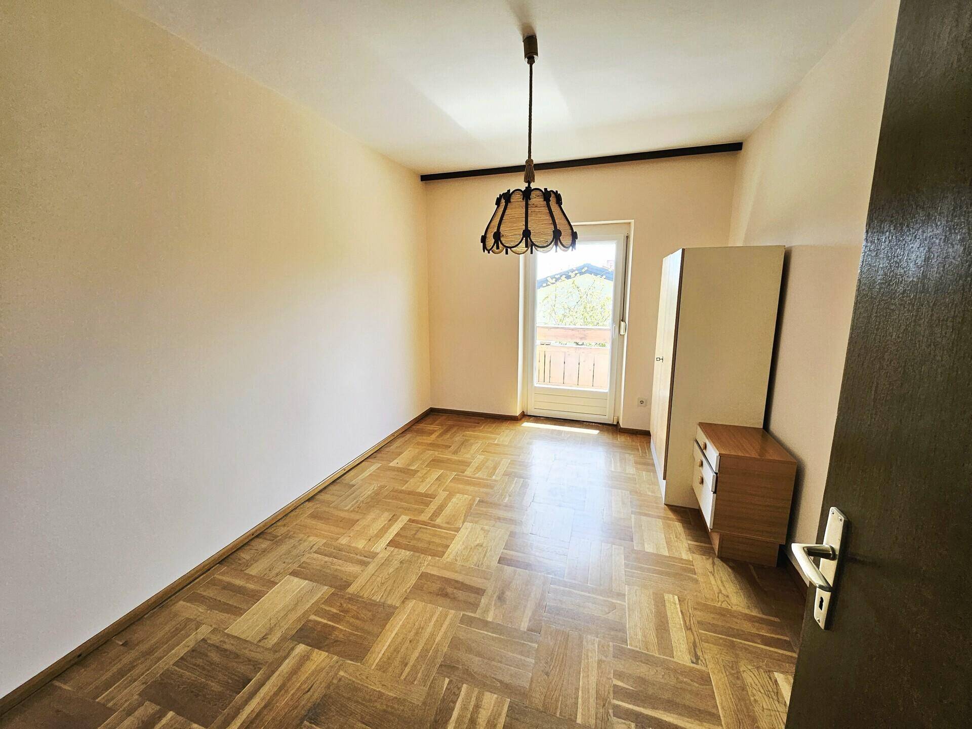 Schlafzimmer mit Parkettboden und direktem Zugang zu einem kleinen Balkon.