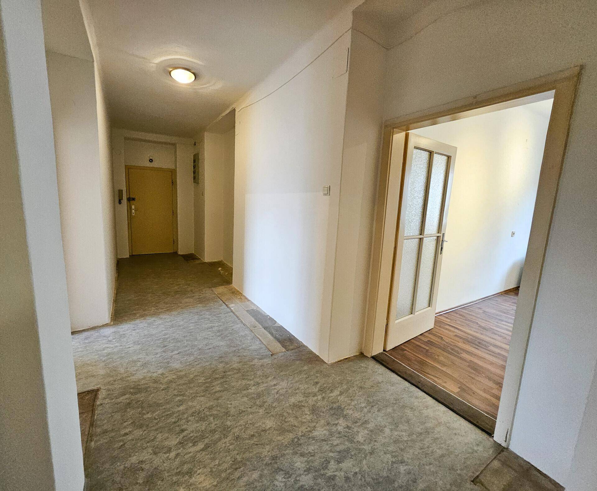 Heller Flur mit Türen zu den Wohnräumen und einem Blick in ein angrenzendes Zimmer.