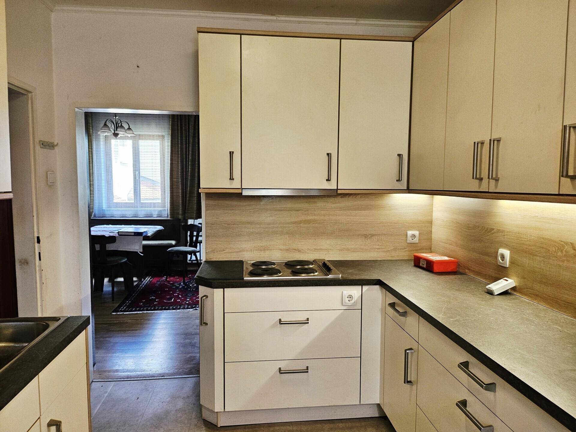 Funktionale Küche mit hellen Schränken und Blick in einen angrenzenden Essbereich.
