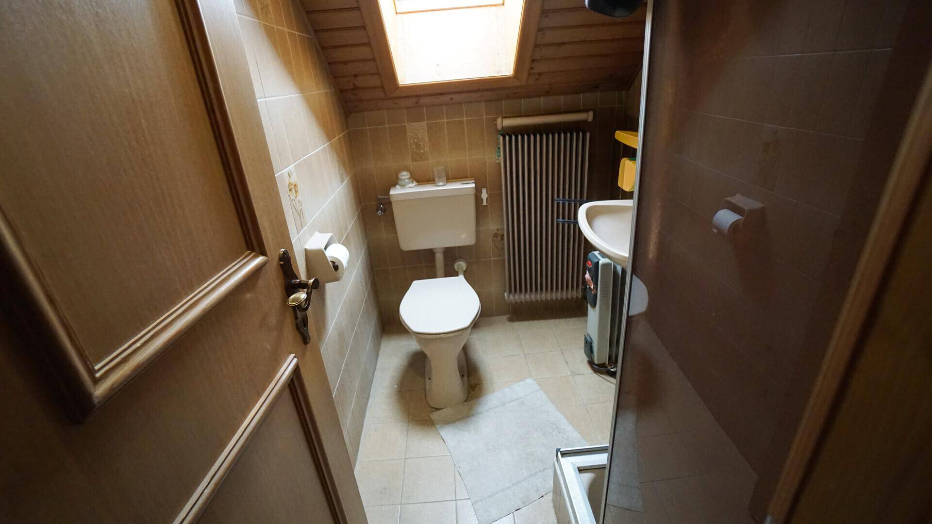 Badezimmer im Dachgeschoss mit Dachfenster, WC, Waschbecken und Heizkörper.