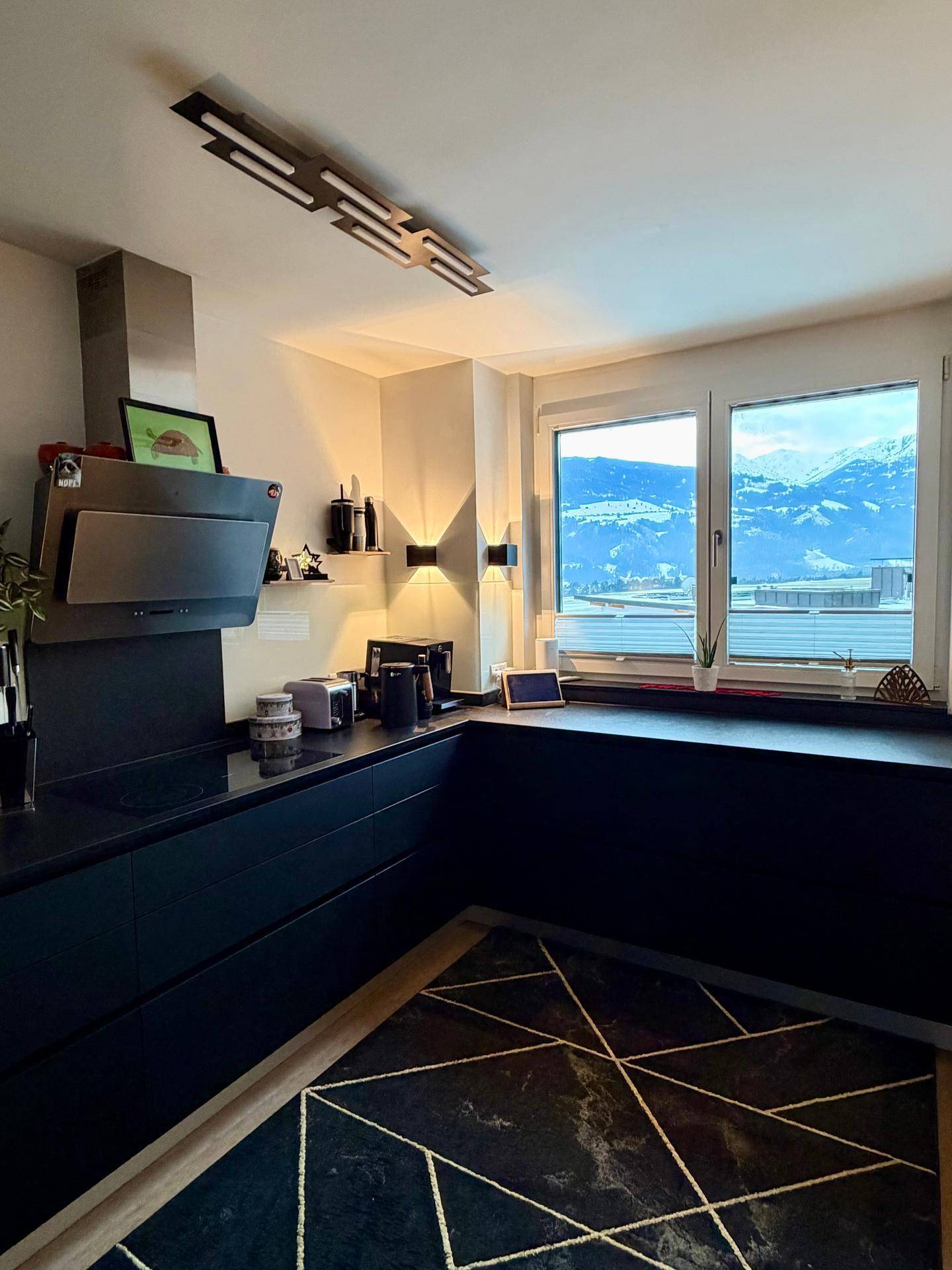 Moderne Küche mit schwarzen Schränken und Arbeitsplatten, bietet einen beeindruckenden Bergblick durch das Fenster.