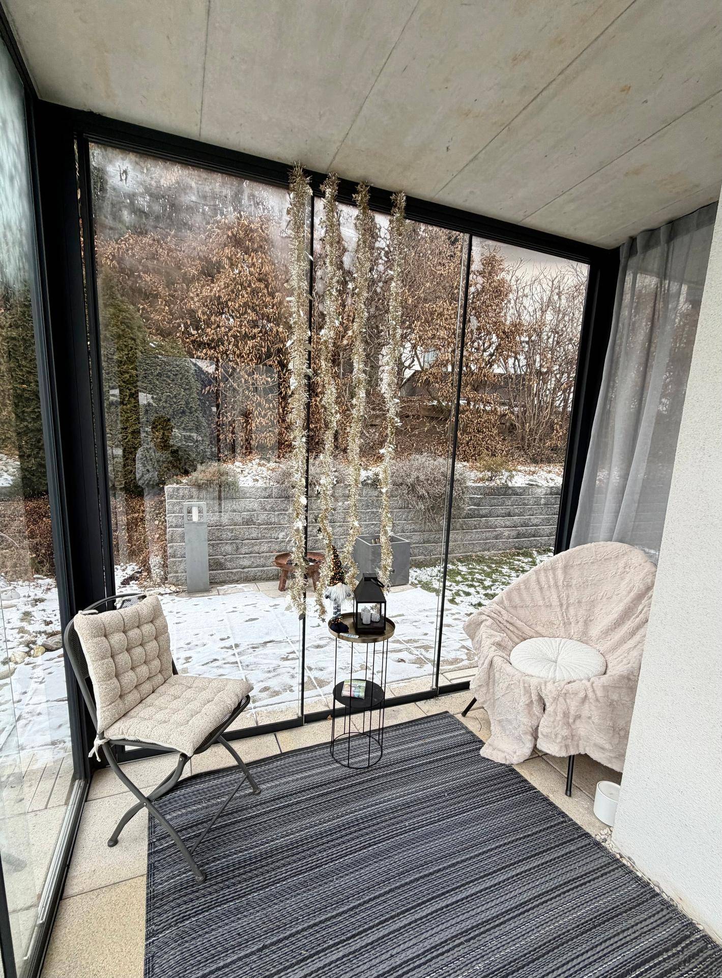 Verglaste Loggia mit Sitzgelegenheiten und Blick auf den verschneiten Garten, ideal zum Entspannen.