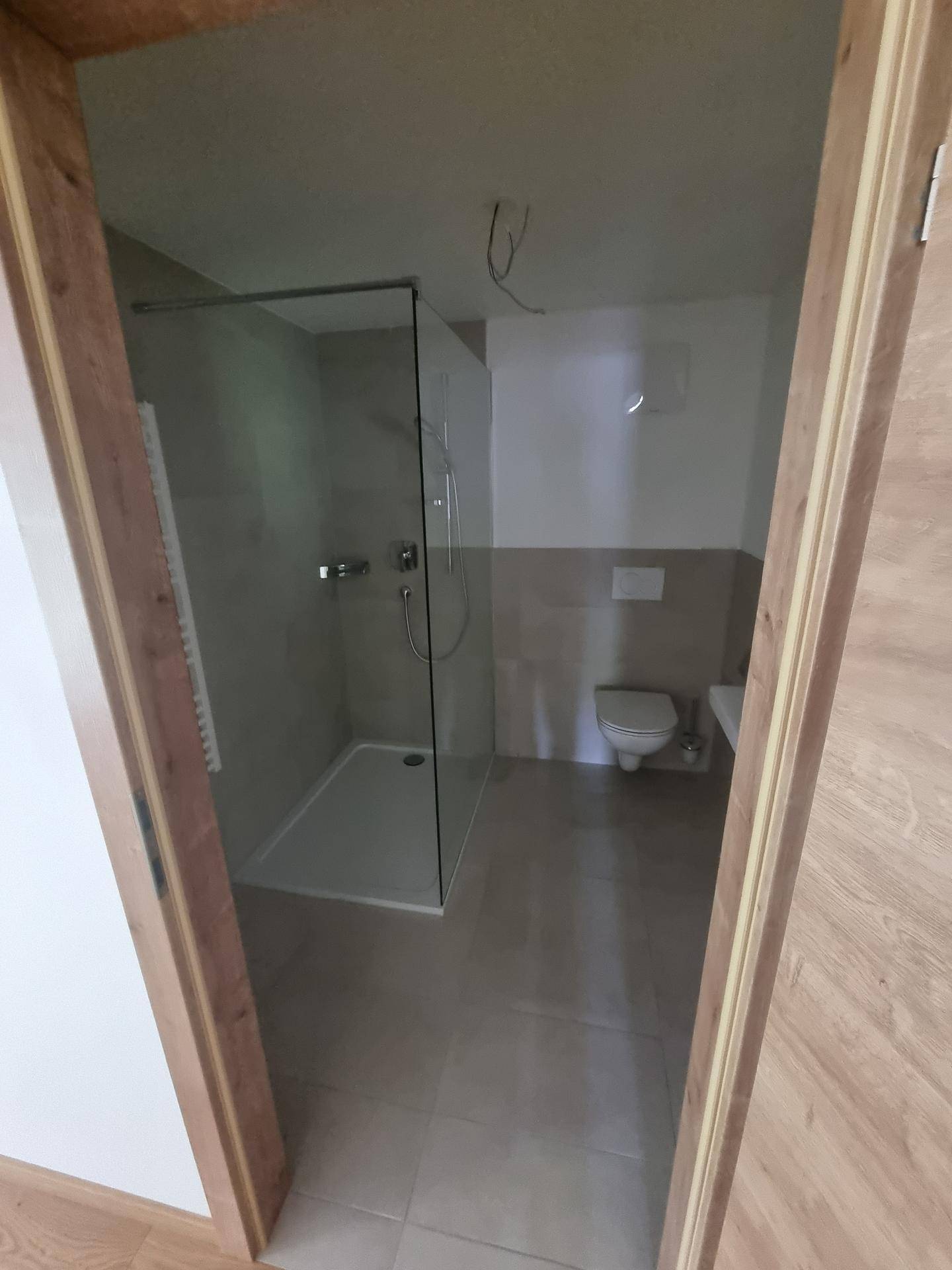 Helles Badezimmer mit moderner Dusche, WC und Waschbecken, ausgestattet mit Fliesenboden.