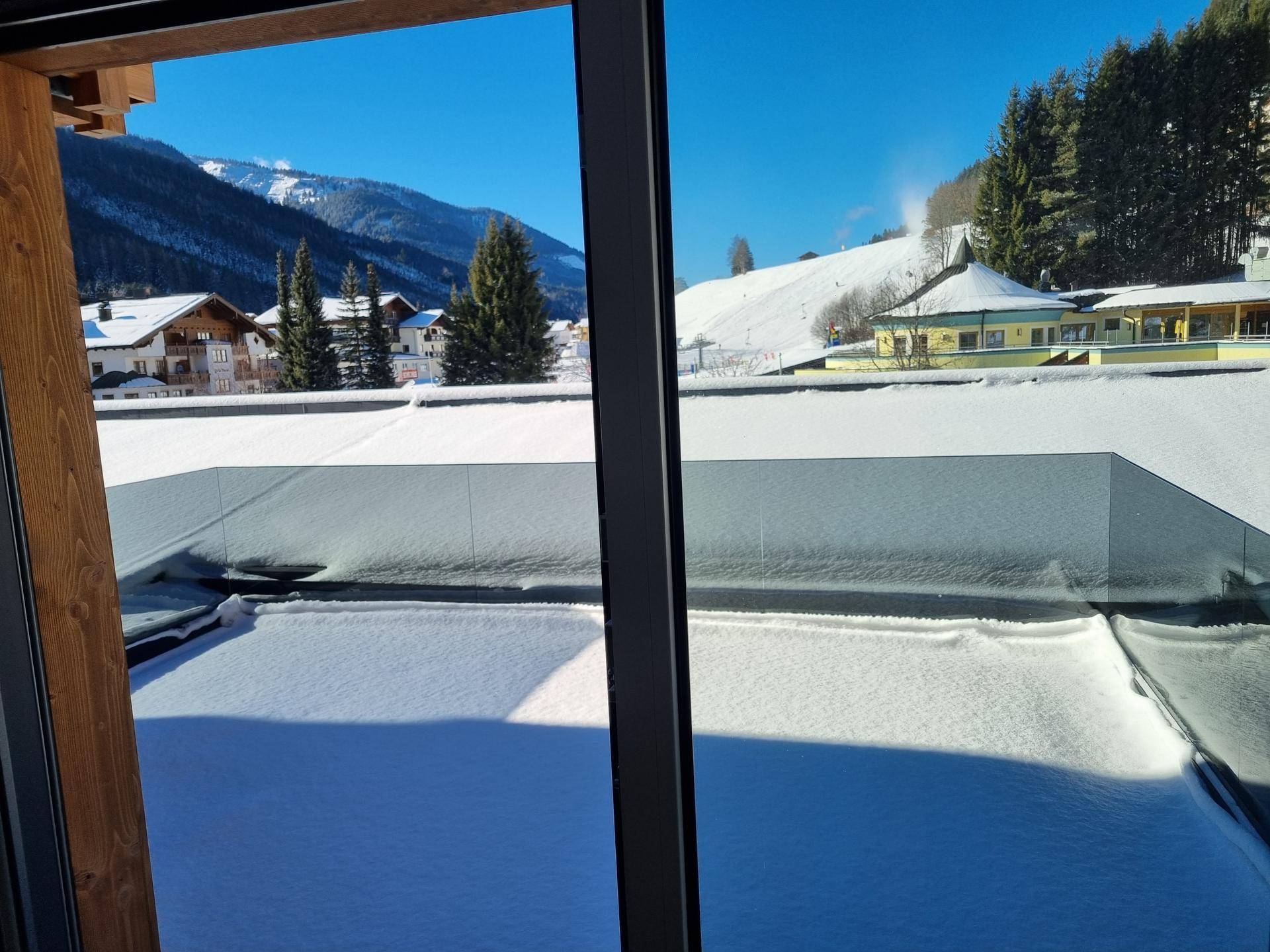 Winterliche Terrasse mit Schnee bedeckt und klarem Blick auf die verschneite Berglandschaft.