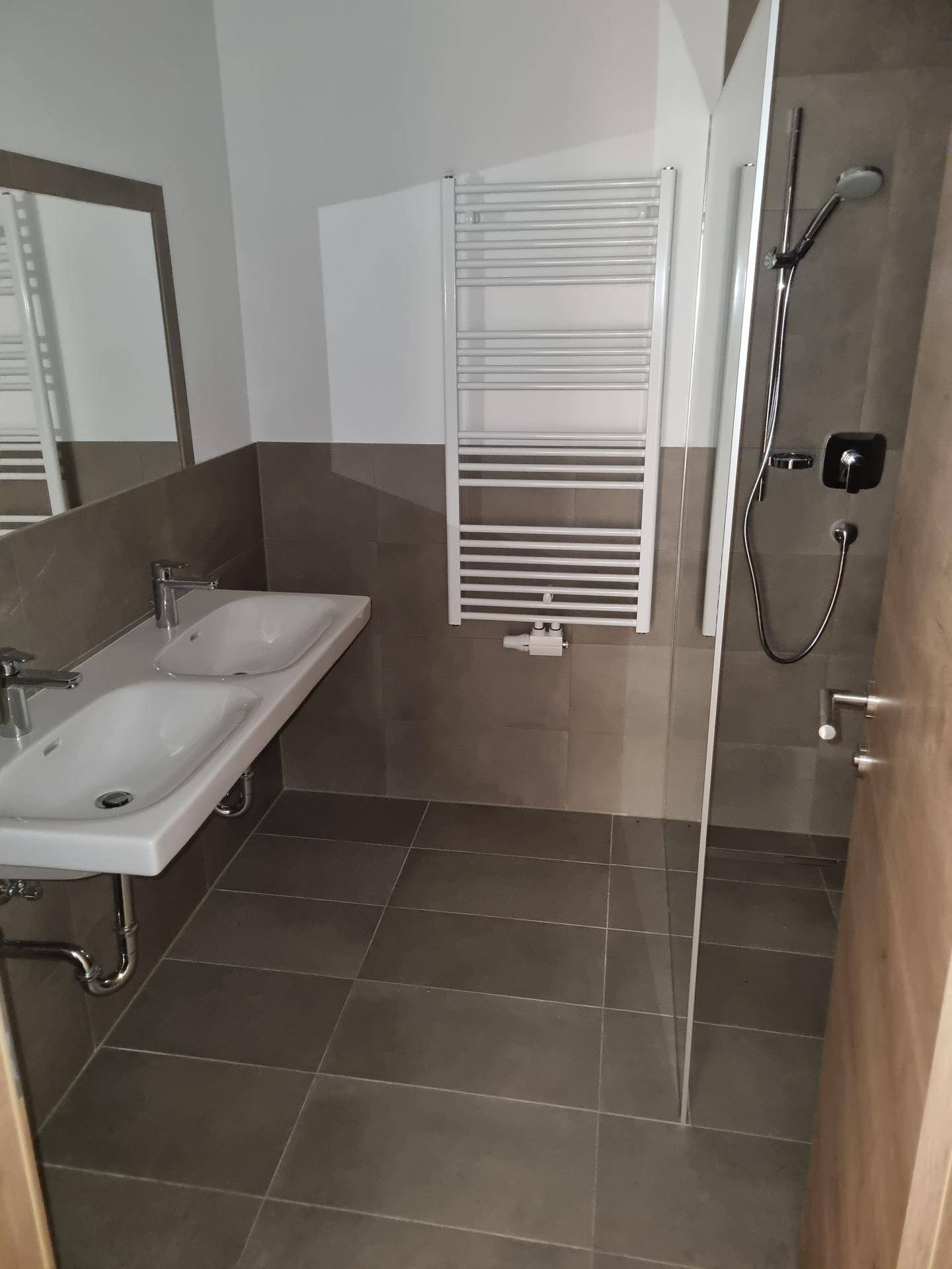 Modernes Badezimmer mit Doppelwaschbecken, ebenerdiger Dusche und beheiztem Handtuchhalter.