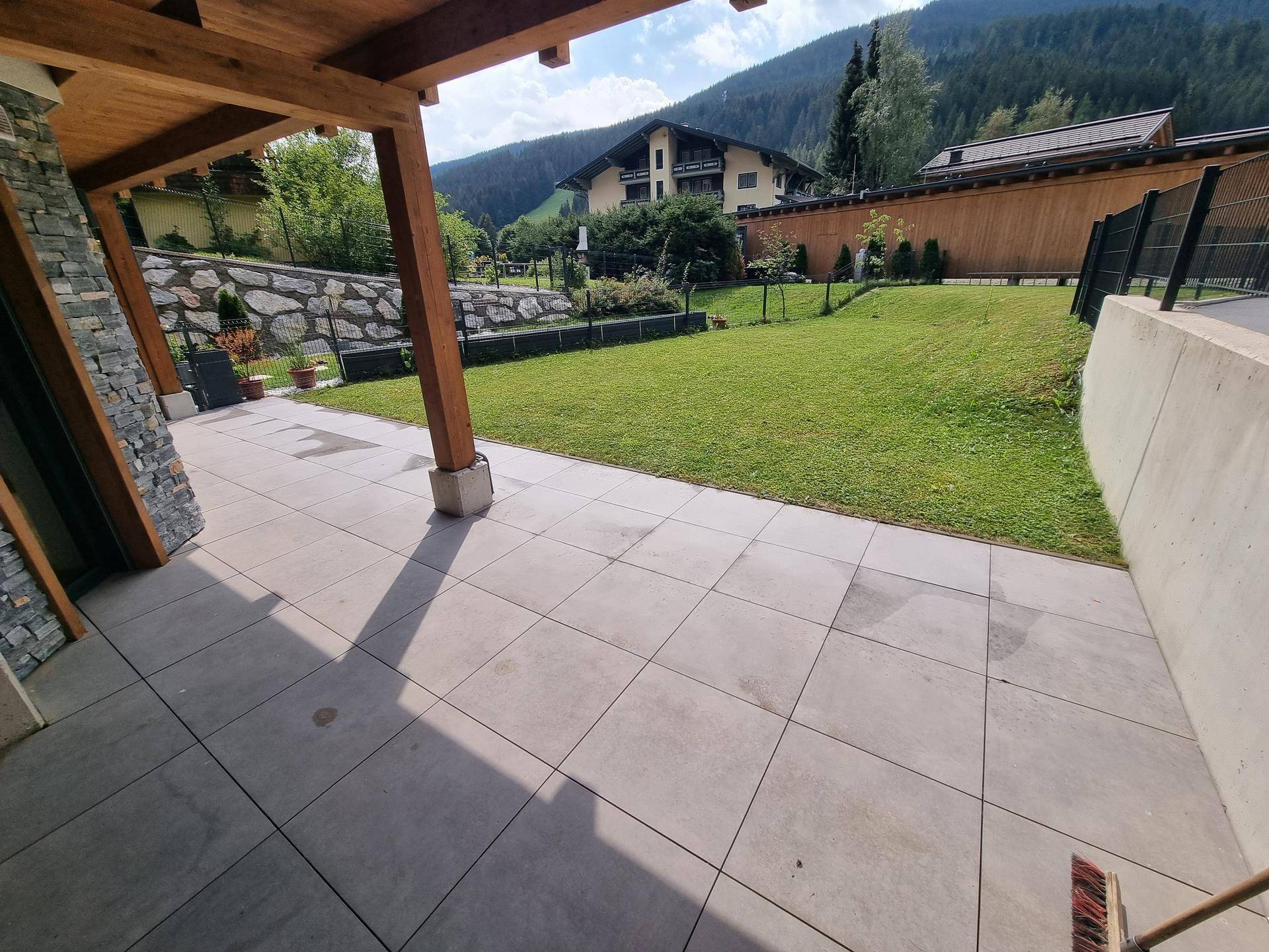 Gepflegter Gartenbereich mit Rasenfläche, Terrasse und Blick auf die umliegende Berglandschaft.