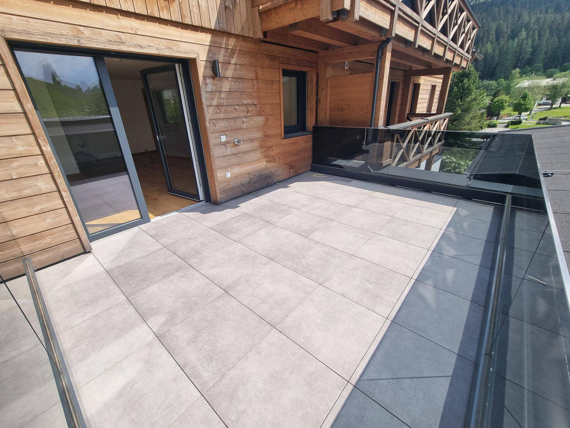 Große Terrasse mit Holzelementen an der Fassade und Zugang zum Innenbereich des Hauses.