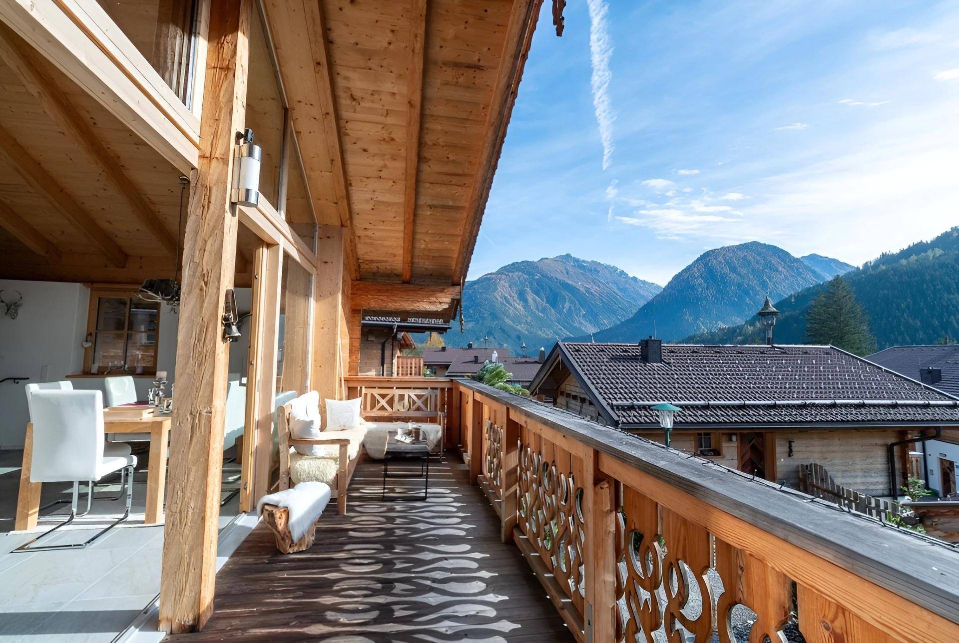 Geräumiger Holzbalkon mit Sitzgelegenheiten und atemberaubendem Blick auf die umliegenden Berge.
