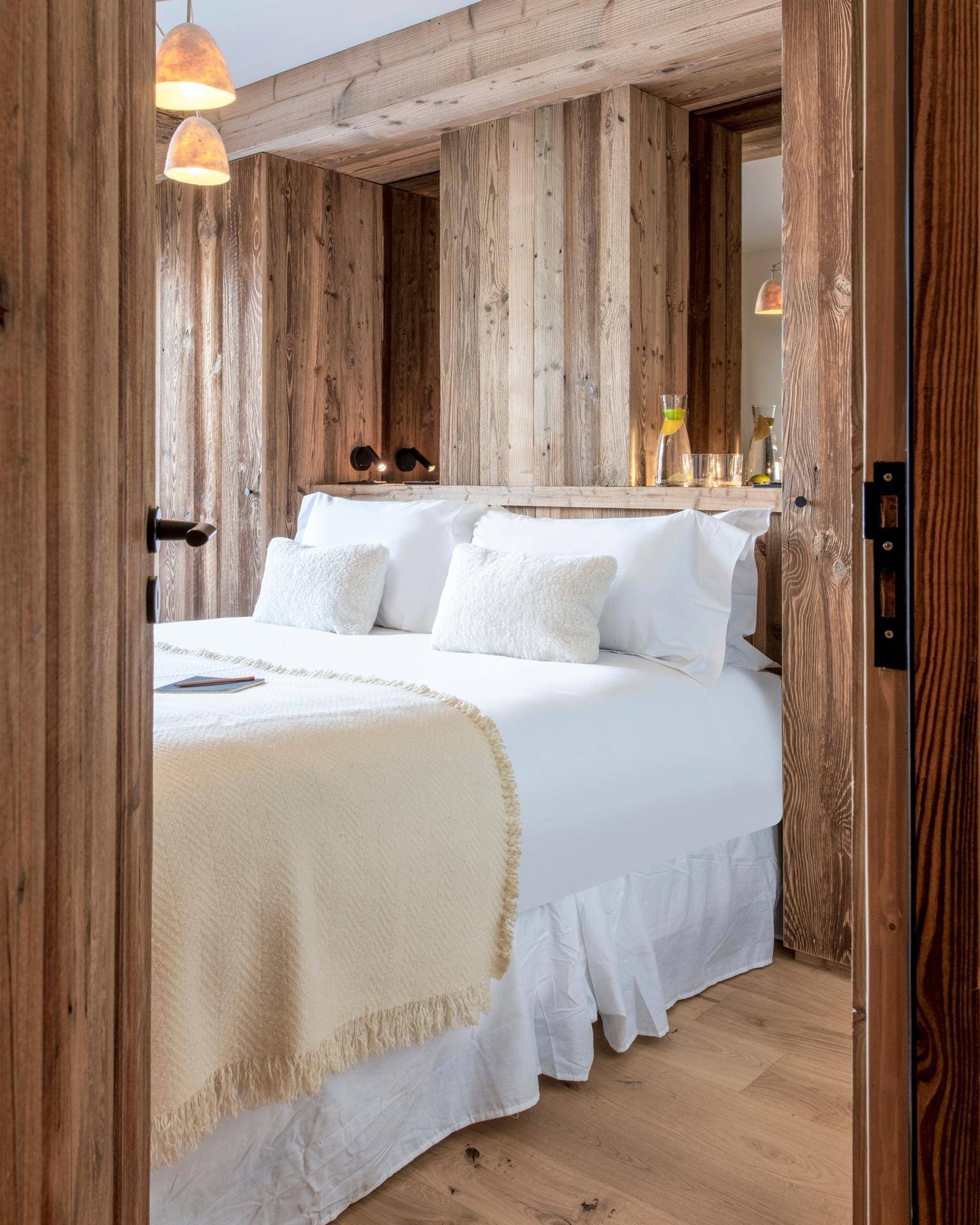 Gemütliches Schlafzimmer mit Holzwänden, Doppelbett und weichen Kissen, bietet alpinen Charme.