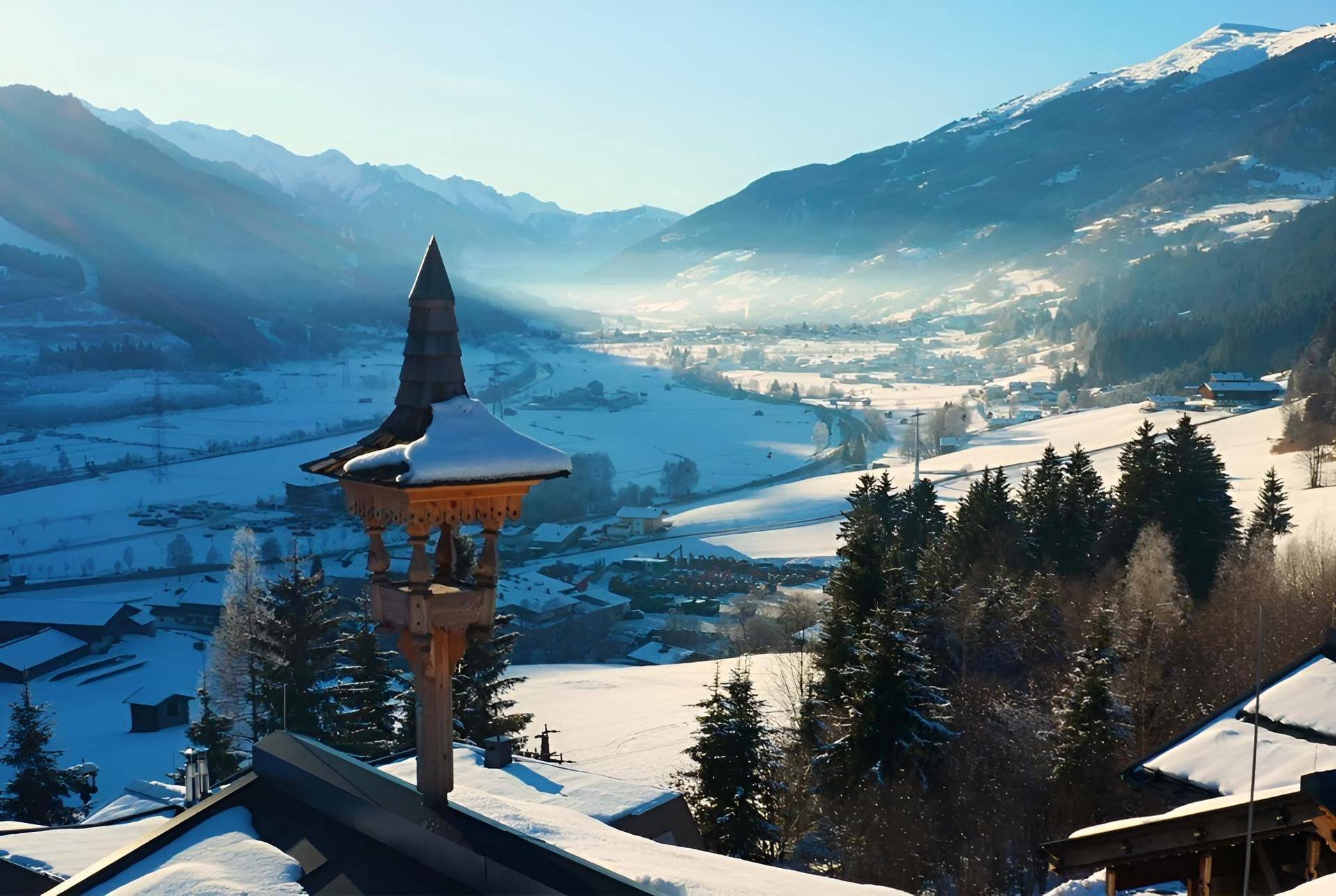 Atemberaubender Panoramablick über ein verschneites Tal und die umliegenden Berge bei Sonnenaufgang.