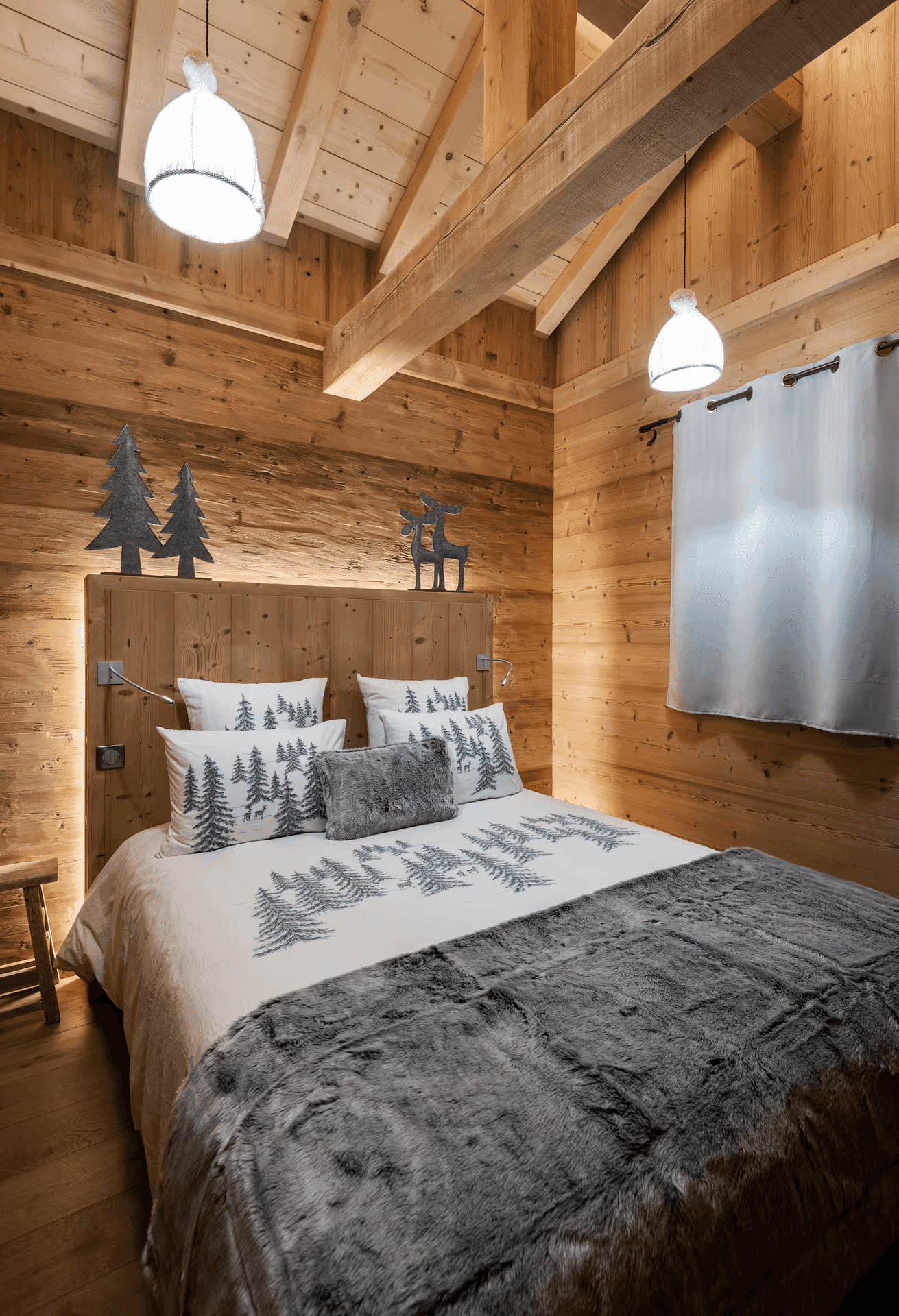 Gemütliches Schlafzimmer im Dachgeschoss mit Holzwänden, Holzbalkendecke und alpiner Bettwäsche.