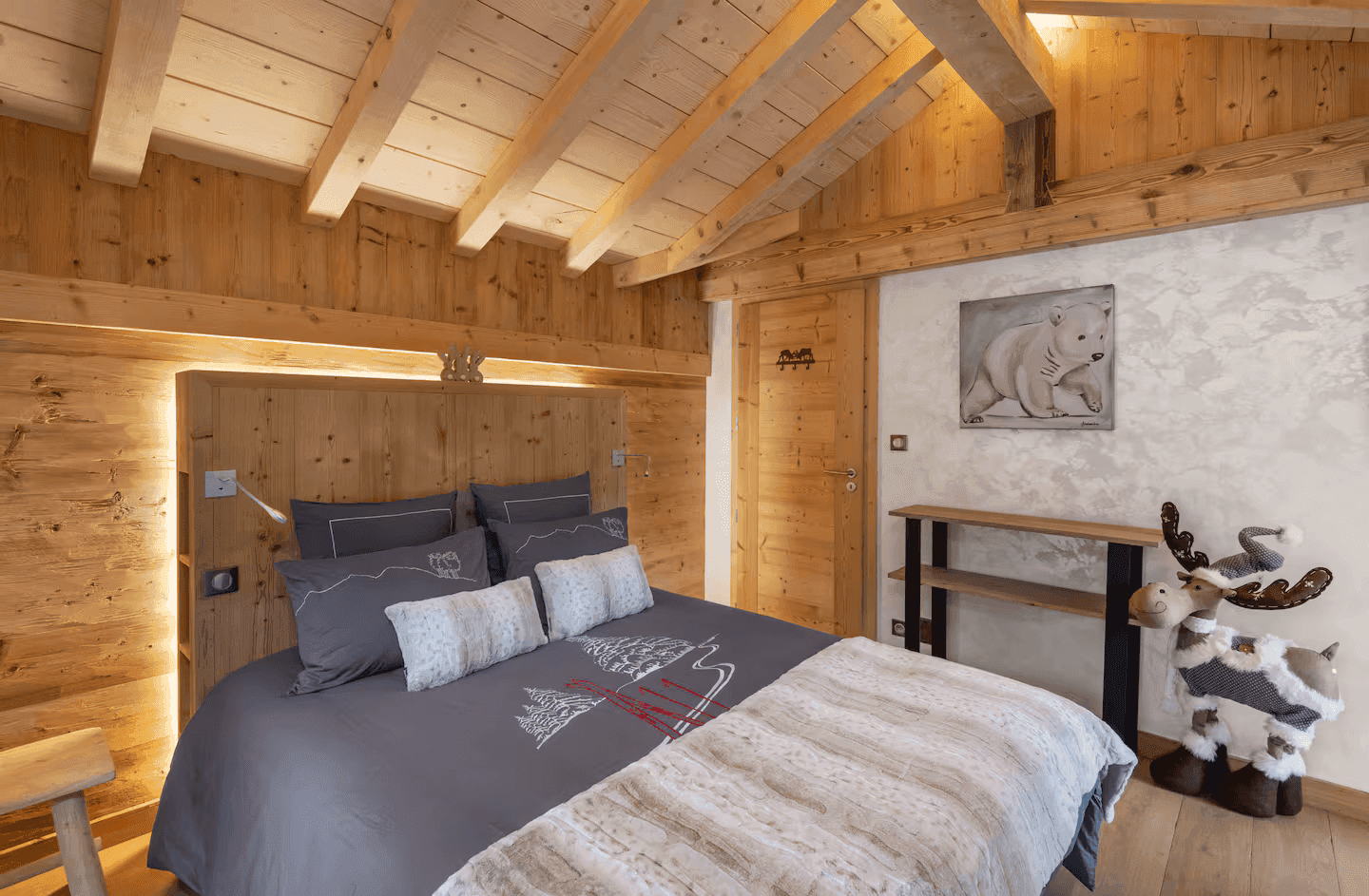 Komfortables Schlafzimmer mit Holzwänden, Holzbalkendecke und alpiner Dekoration.
