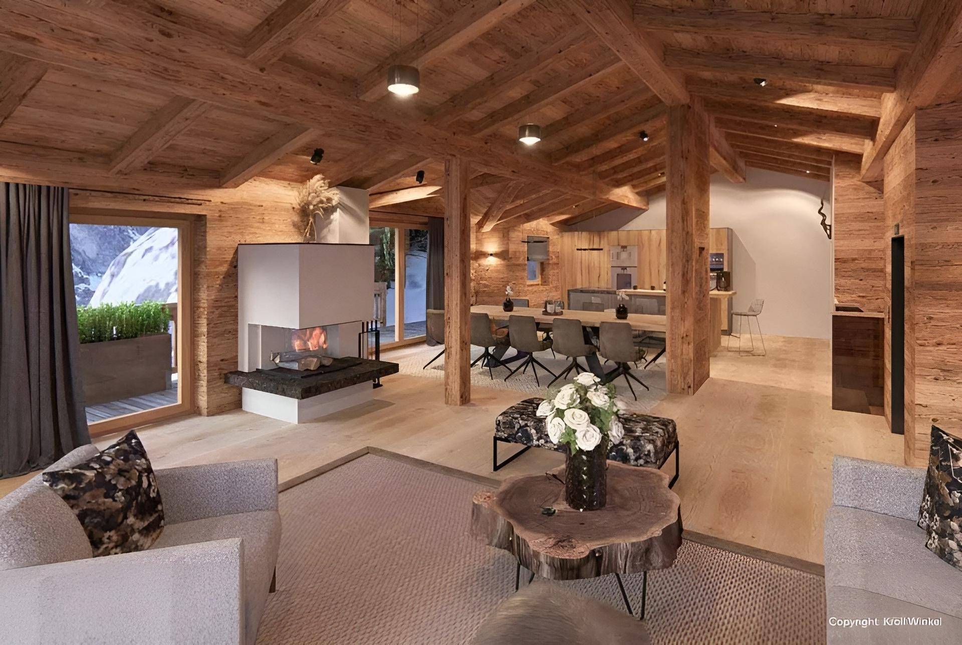 Offener Wohn- und Essbereich im Chalet-Stil mit Kamin, Holzbalken und moderner Einrichtung.