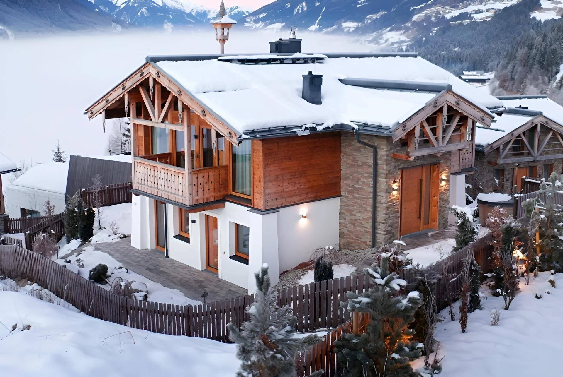 Verschneites Chalet mit moderner Architektur, Holzfassade und atemberaubendem Bergblick.