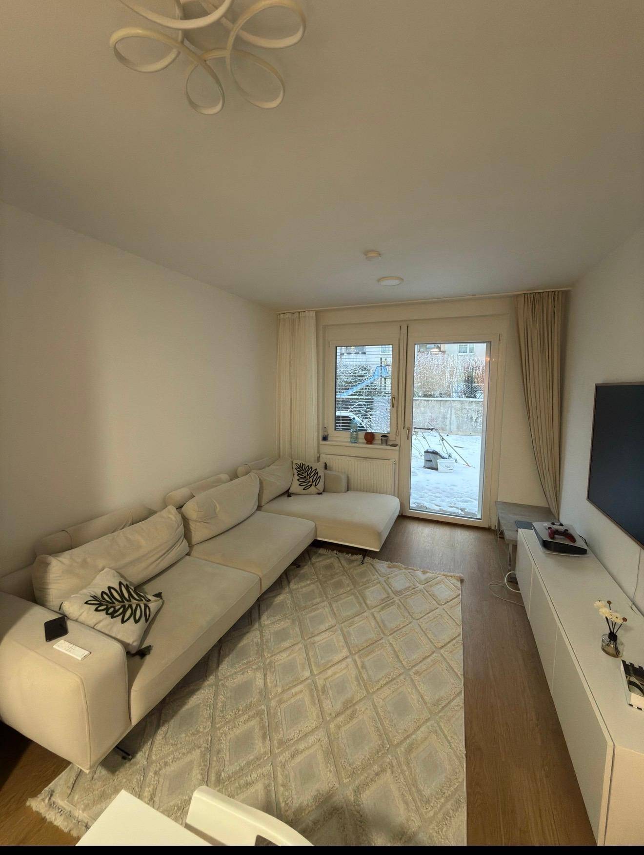 Helles Wohnzimmer mit großem Ecksofa, Holzboden und direktem Zugang zur Terrasse.