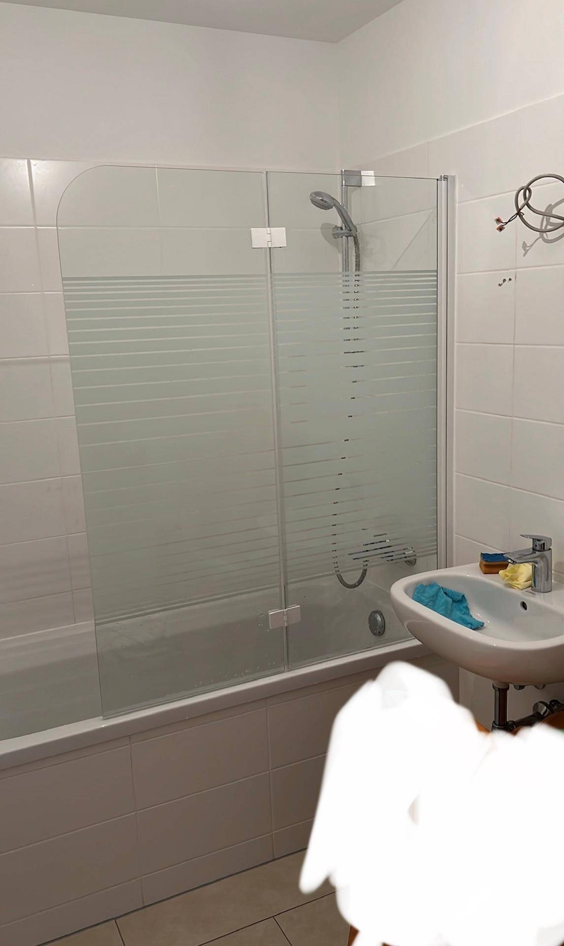 Badezimmer mit Badewanne, Duschabtrennung aus Glas und einem einzelnen Waschbecken.