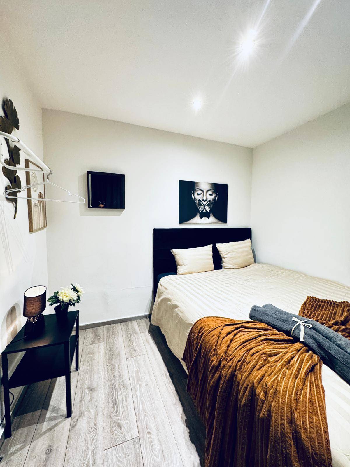 Helles Schlafzimmer mit einem Bett, Nachttisch und moderner Wanddekoration.