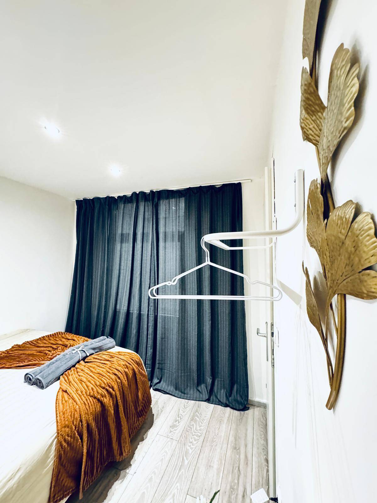 Schlafzimmer mit dunklen Vorhängen, Laminatboden und dekorativen Elementen an der Wand.