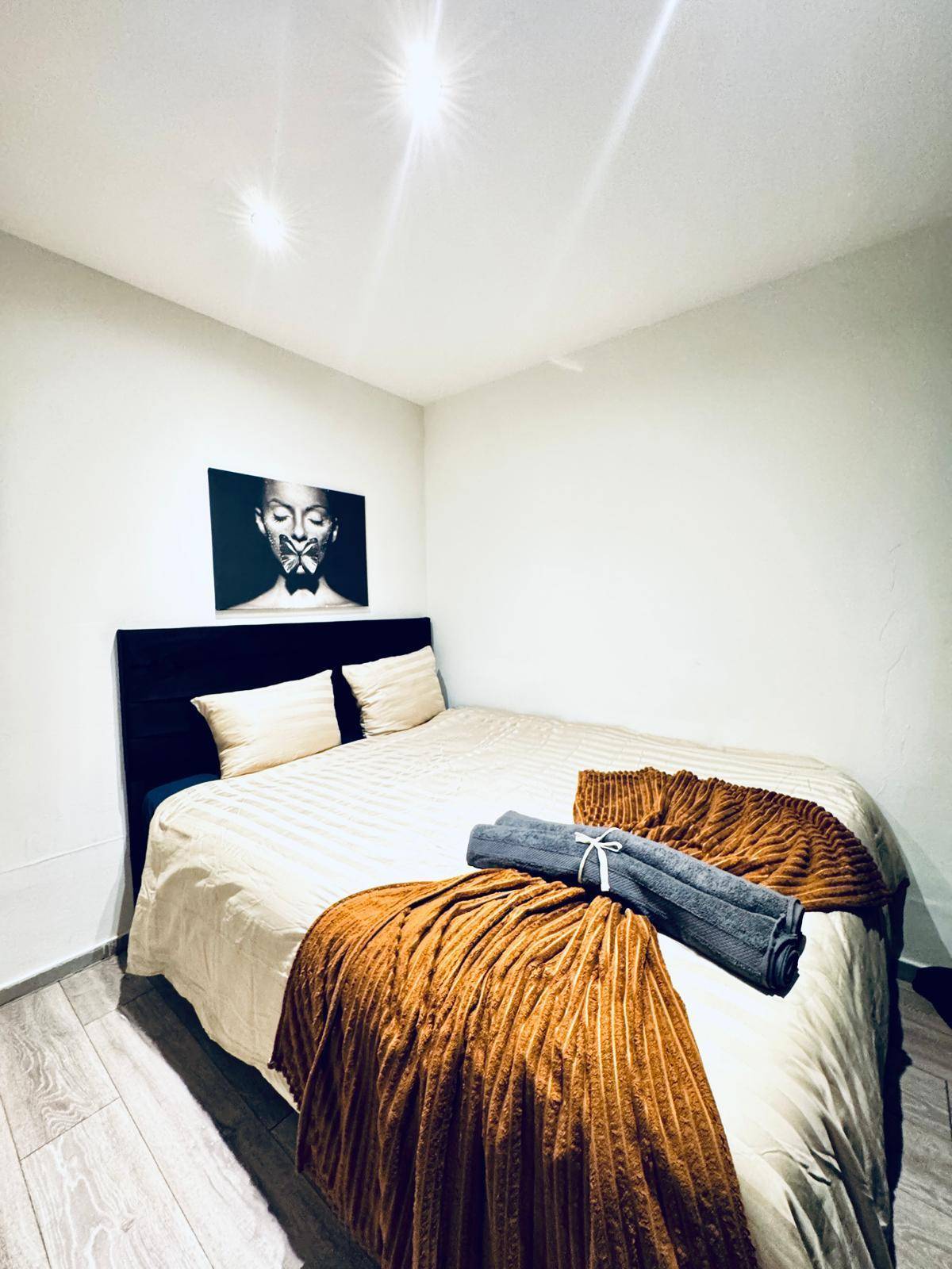 Schlafzimmer mit Doppelbett, minimalistischer Dekoration und Laminatboden.