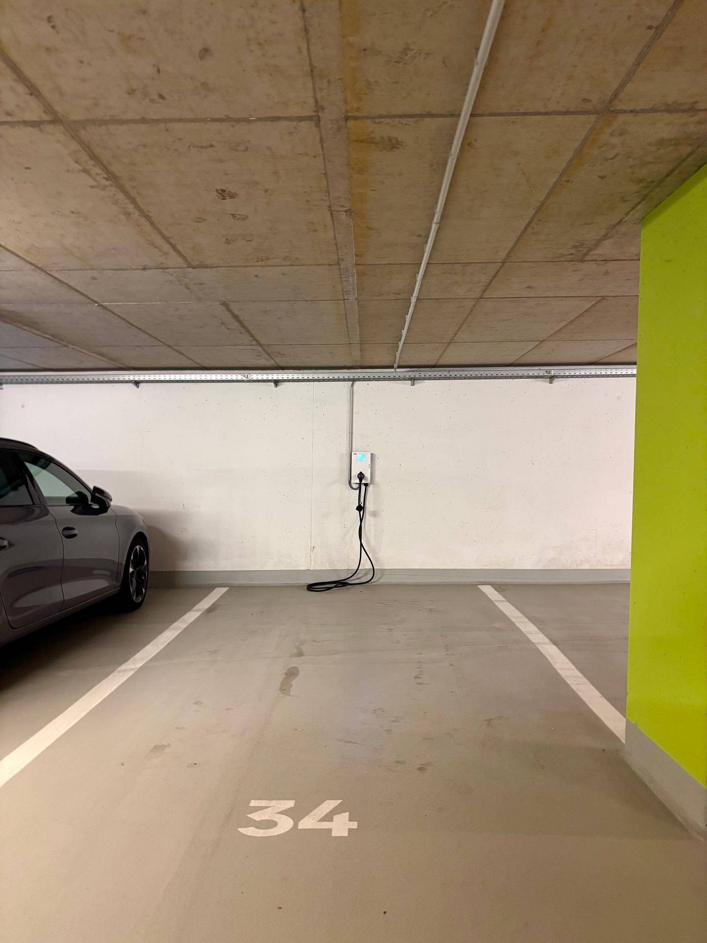 Tiefgaragenstellplatz mit Ladestation für Elektrofahrzeuge, gut beleuchtet und geräumig.
