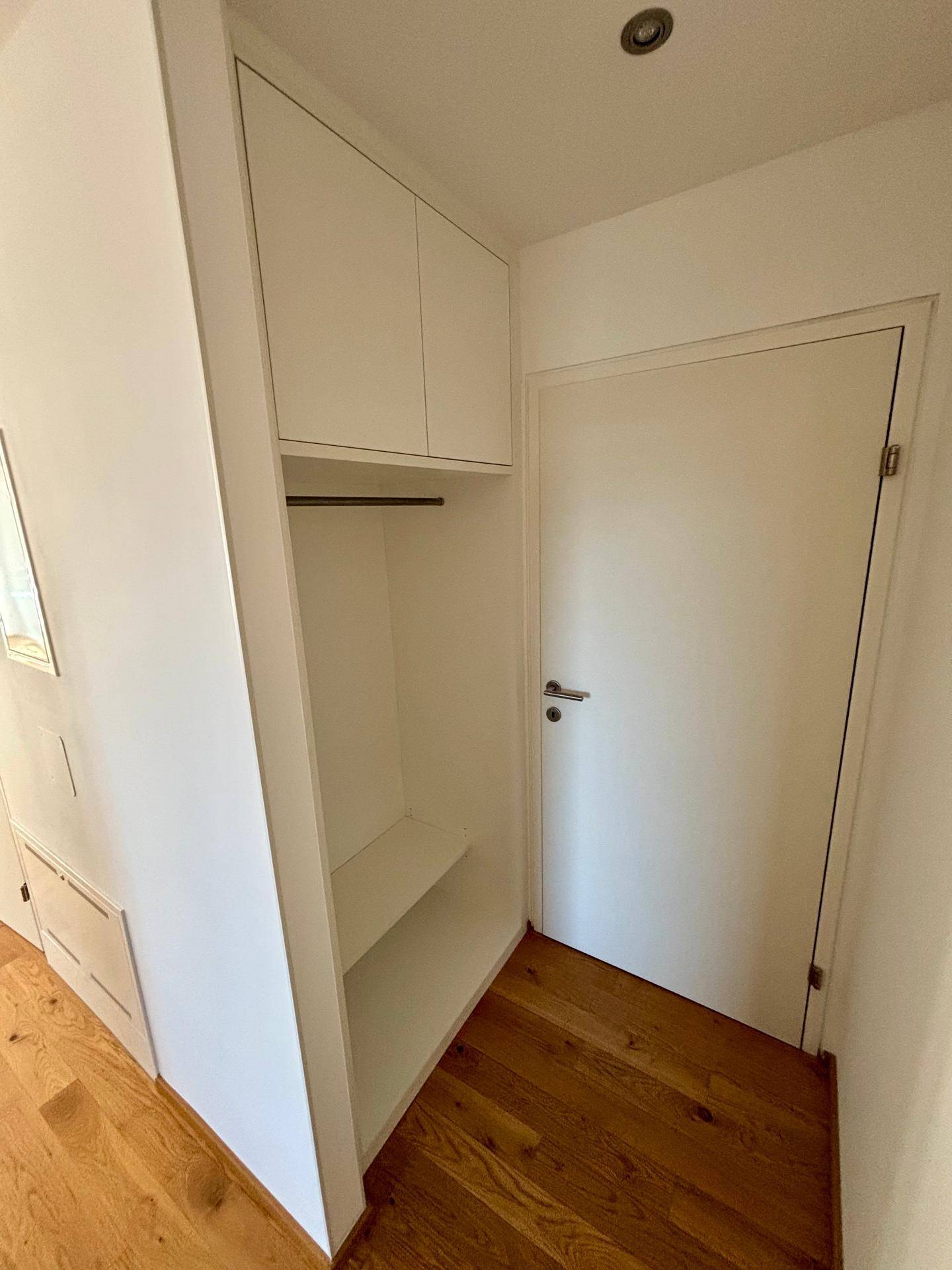 Heller Flur mit Holzboden und praktischen weißen Einbauschränken für zusätzlichen Stauraum.