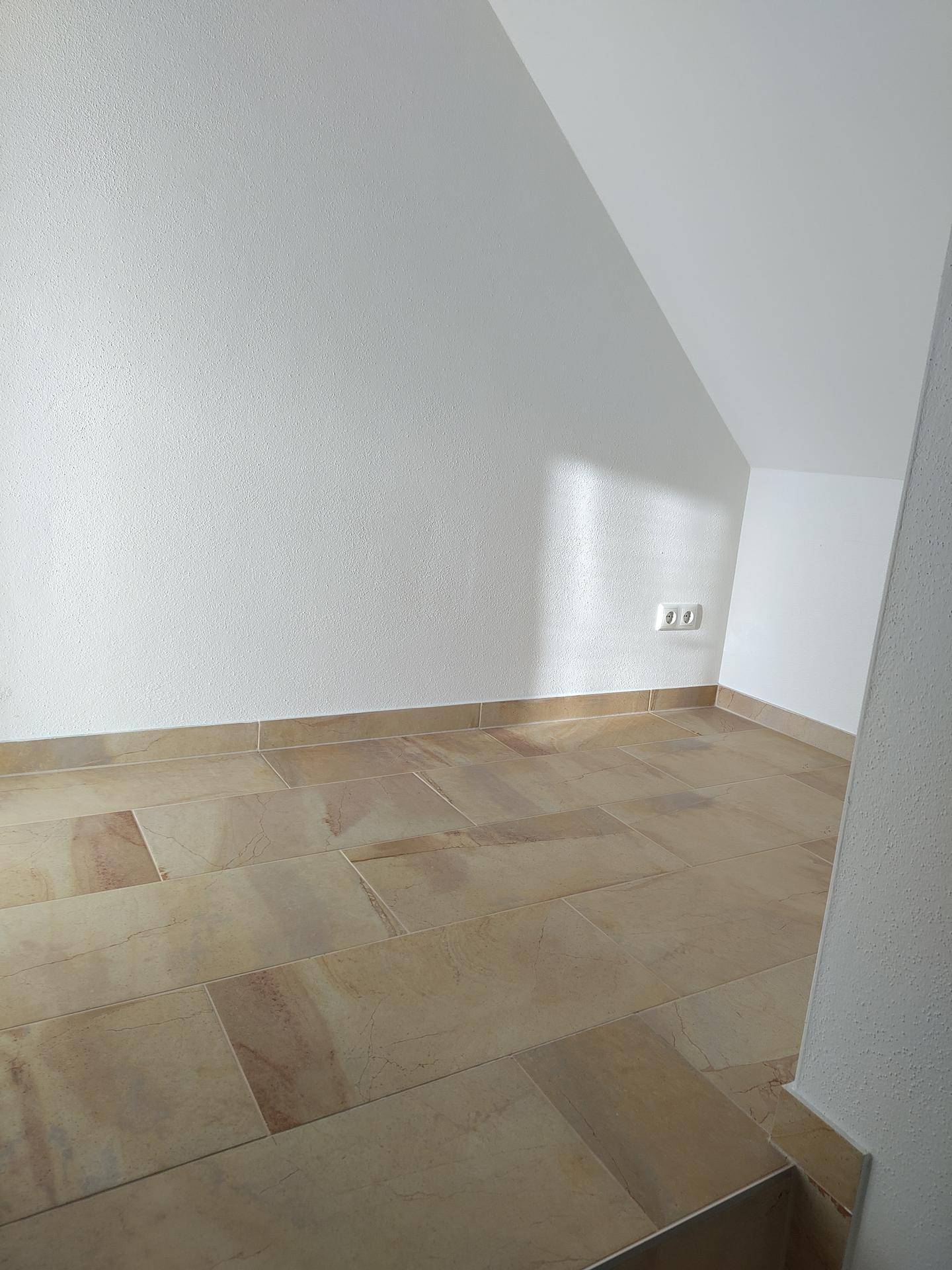 Kleiner Raum mit Fliesenboden und Dachschräge, geeignet als Abstellraum oder begehbarer Schrank.