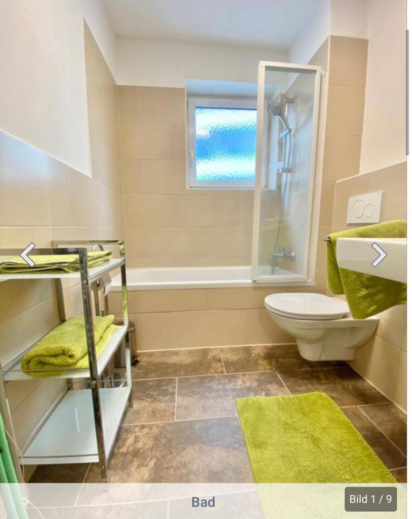 Modernes Badezimmer mit Badewanne, Duschabtrennung, WC und Fenster für Belüftung.