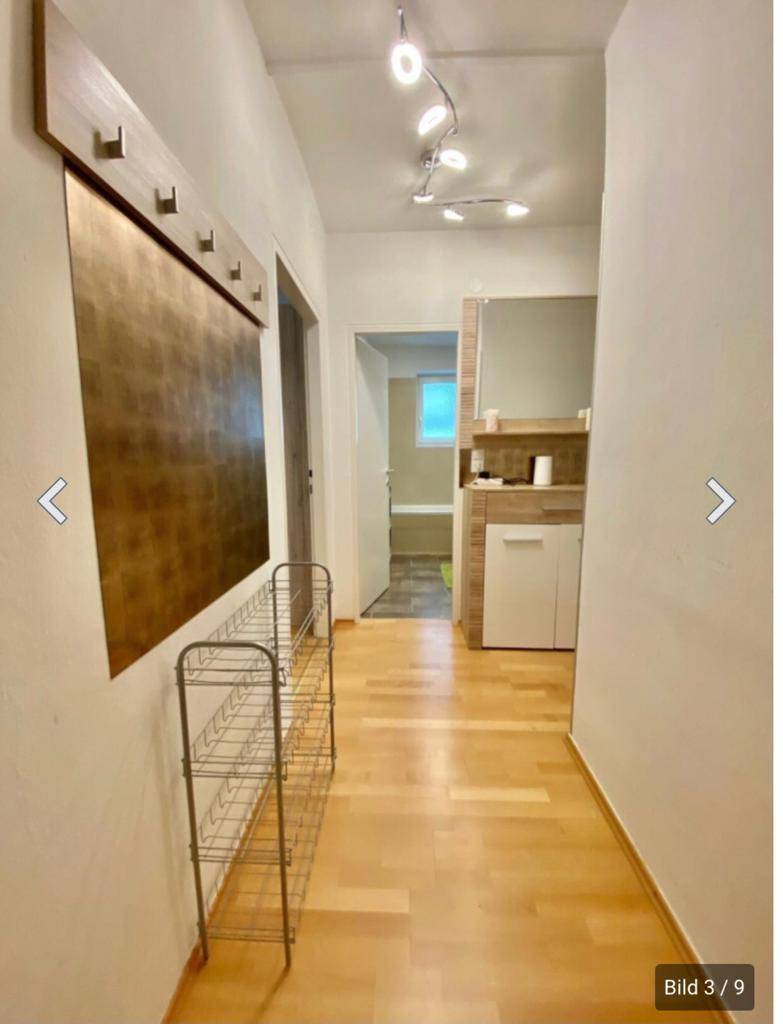 Langer Flur mit Holzfußboden und Garderobe, der zu weiteren Räumen führt.