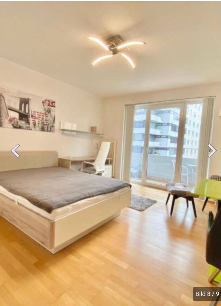 Helles Schlafzimmer mit Balkonzugang, Doppelbett und Blick auf die Umgebung.