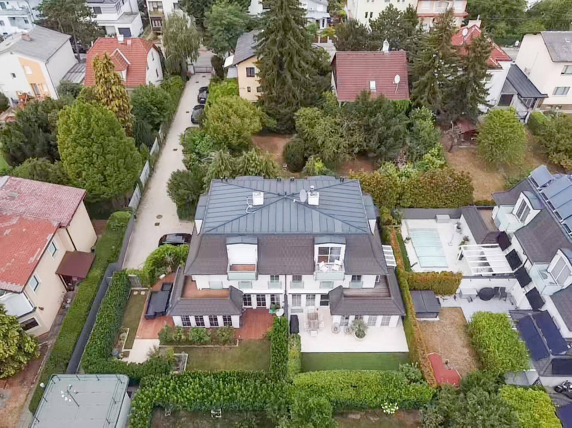 Luftaufnahme eines modernen Wohnhauses mit Garten und umliegender Wohnbebauung.