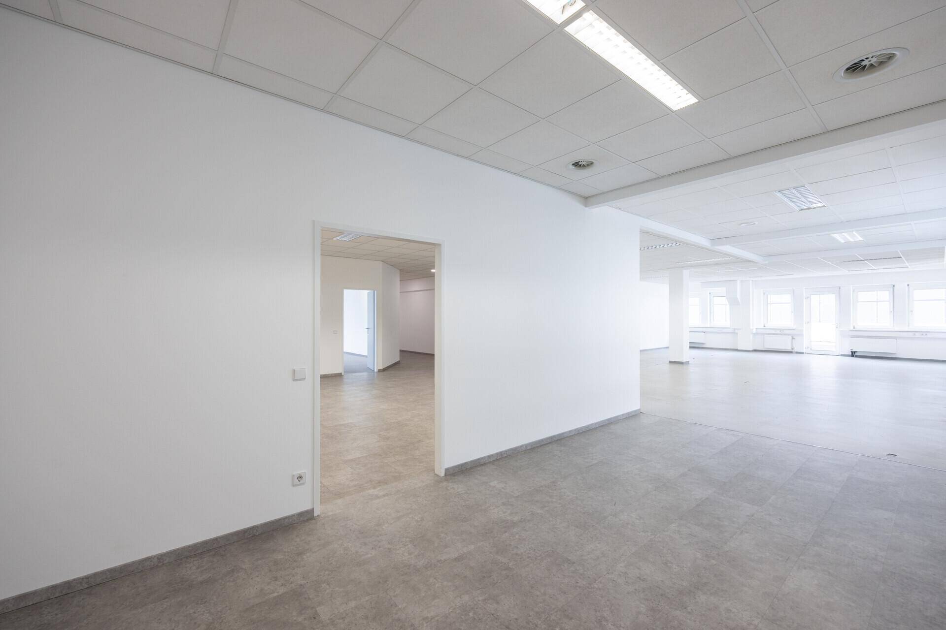 Heller, offener Bürobereich mit grauen Fliesenböden und weißen Wänden, ideal für flexible Arbeitsplatzgestaltung.