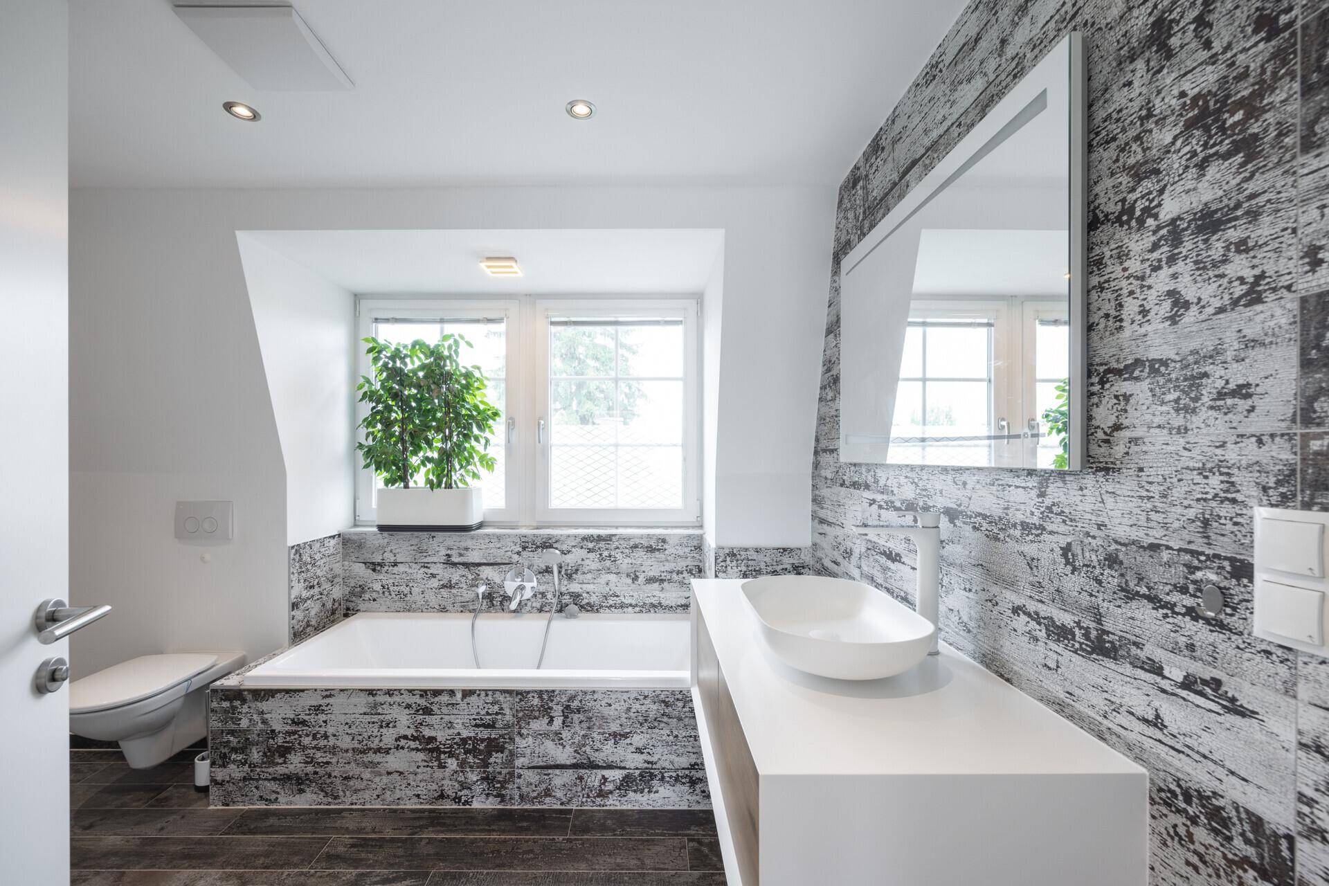 Modernes Badezimmer mit Badewanne, stilvollen Fliesen und Fenster für natürliches Licht.