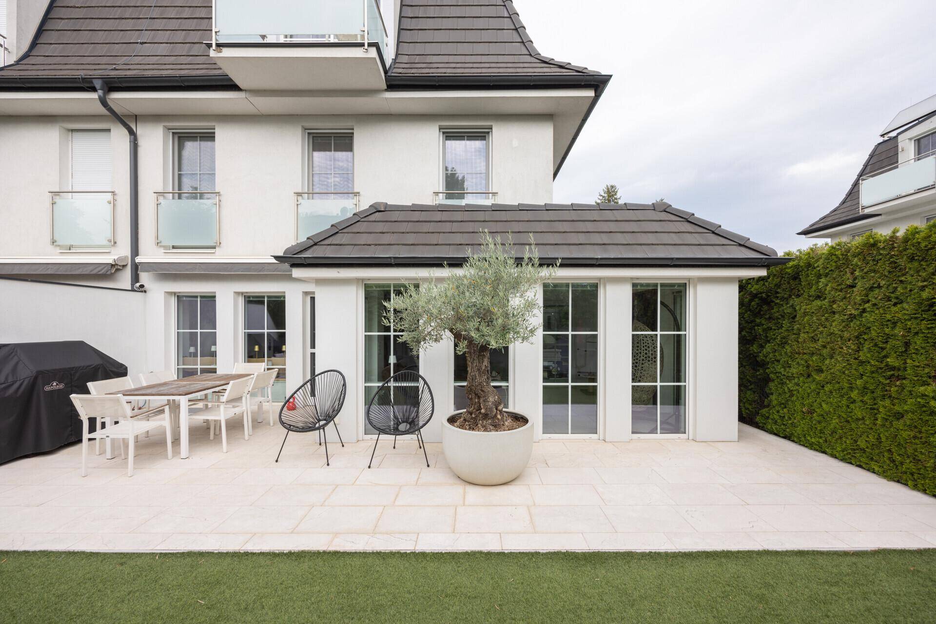 Große Terrasse mit Essbereich und Blick auf den gepflegten Garten, ideal für Mahlzeiten im Freien.