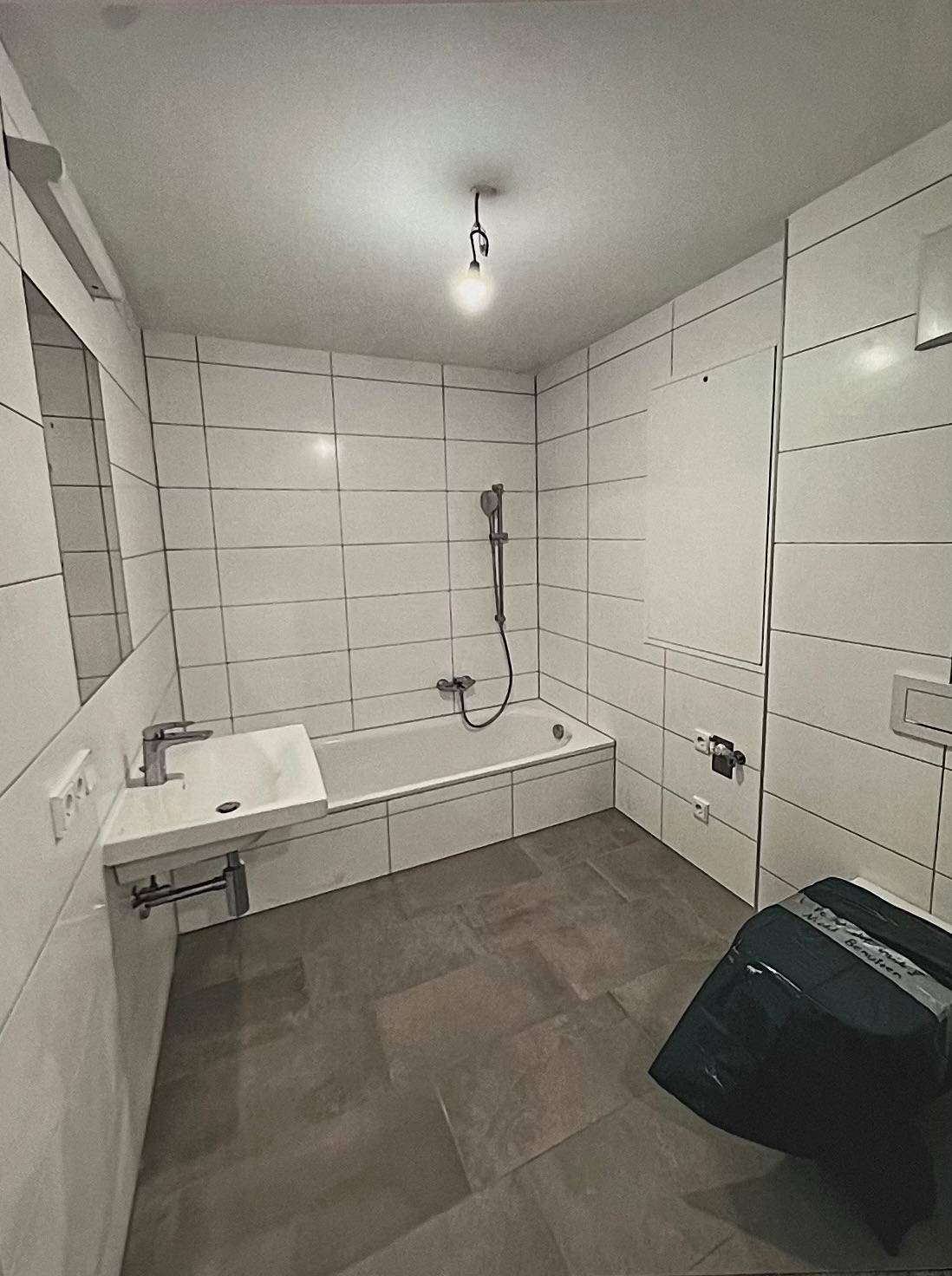 Modernes Badezimmer mit weißen Fliesen, Badewanne und Waschbecken.