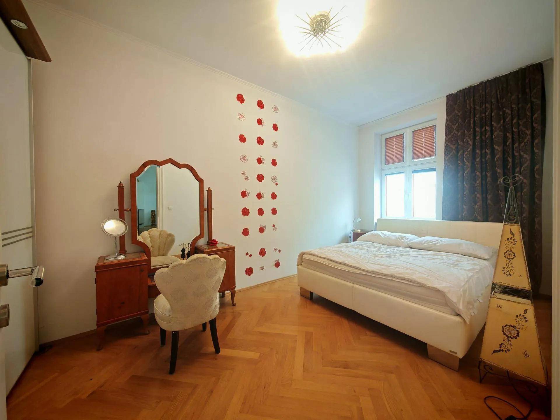 Schlafzimmer mit Doppelbett, Schminktisch und Fischgrätparkett.