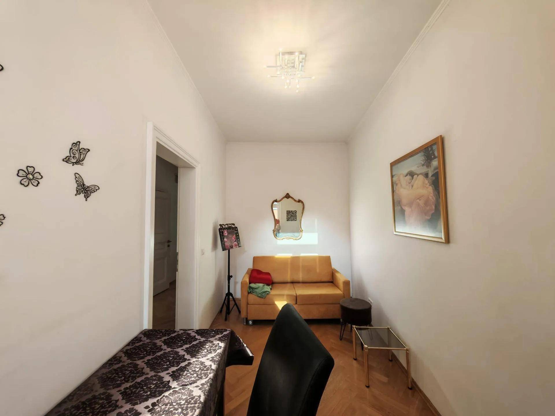 Helles Zimmer mit Parkettboden, gelbem Sofa und dekorativen Wandelementen.