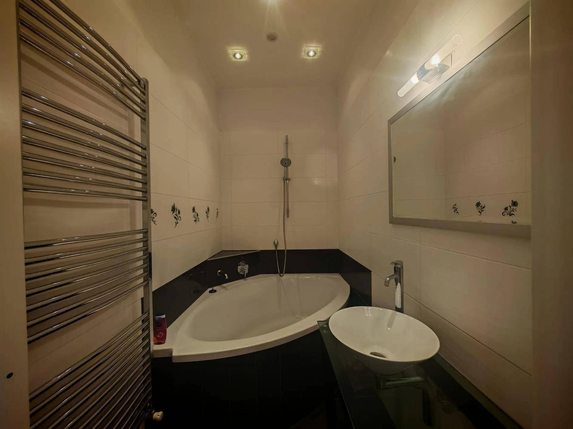 Modernes Badezimmer mit Eckbadewanne, beheiztem Handtuchhalter und Aufsatzwaschbecken.