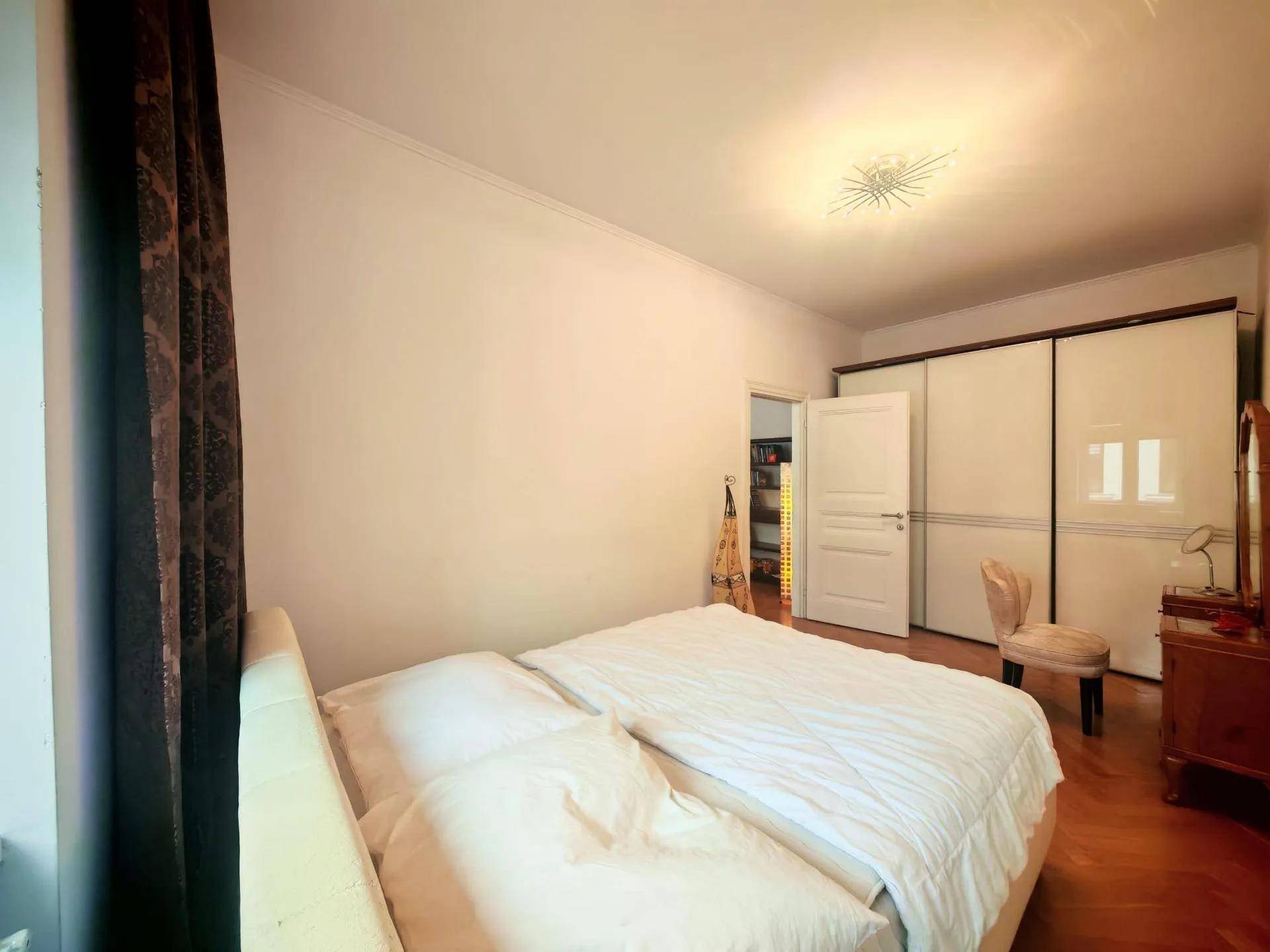 Schlafzimmer mit großem Bett, Einbauschränken und Fischgrätparkett.