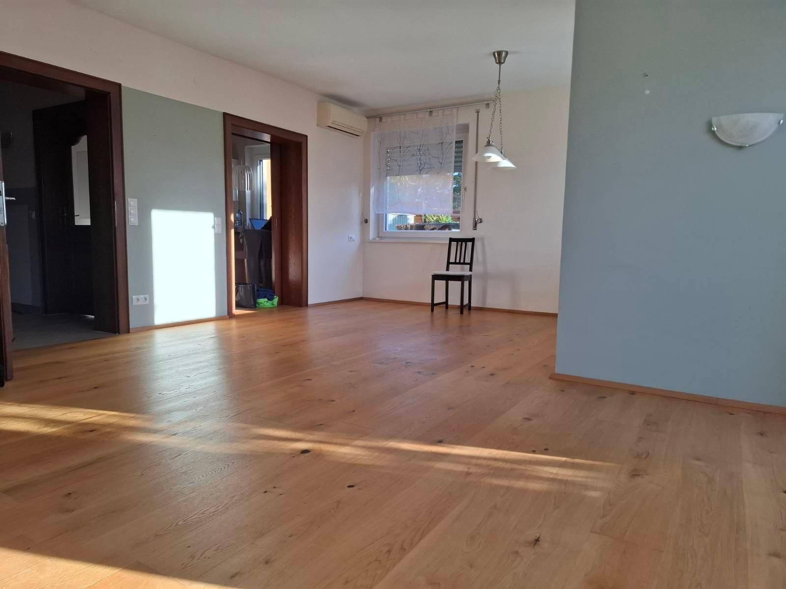 Helles Wohnzimmer mit Holzboden, hellblauen Wänden und Klimaanlage.