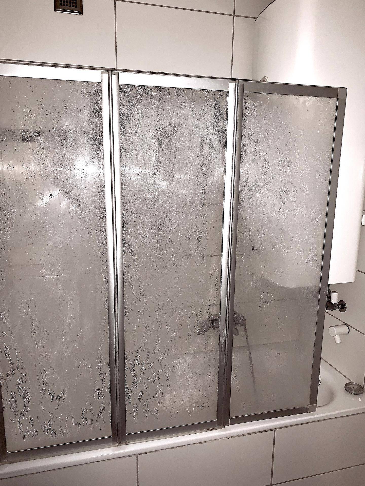 Badezimmer mit Badewanne und einer Duschabtrennung aus Glas.