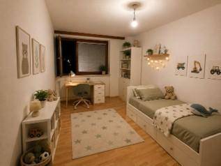 Kinderzimmer mit Einzelbett, Schreibtisch, Regalen und kindgerechter Dekoration, hell und freundlich.