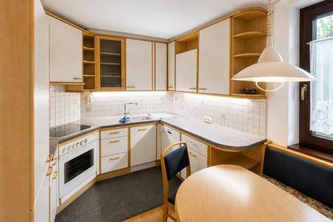 Funktionale Küche mit hellen Holz- und weißen Schränken, integrierten Geräten und einer gemütlichen Essecke.