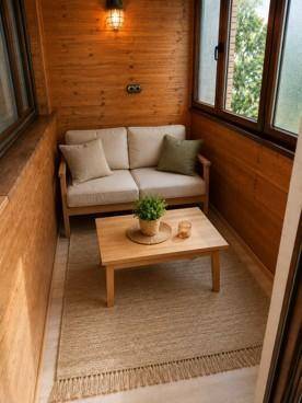 Gemütliche verglaste Loggia mit Holzverkleidung, kleinem Sofa und Couchtisch, ideal zum Entspannen.