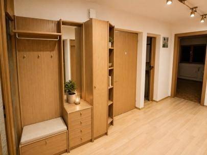 Heller Flur mit Garderobe aus Holz, Spiegel und hellem Parkettboden, einladend gestaltet.