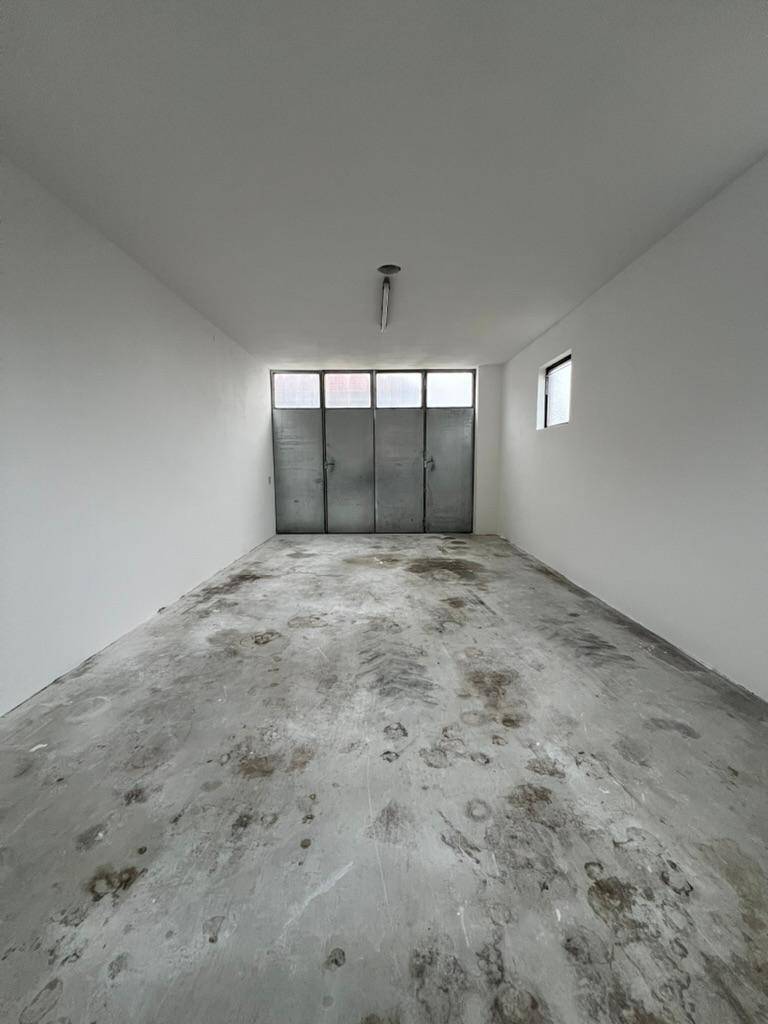 Langer Garagenraum mit Betonboden und großen Metalltoren am Ende des Raumes.