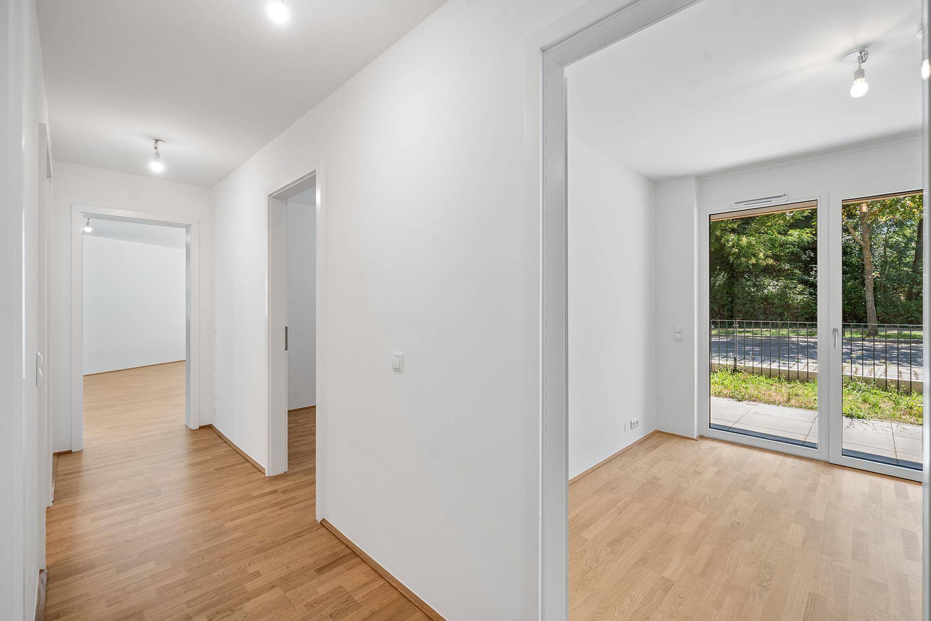 Heller Flur mit Parkettboden und Zugang zu weiteren Räumen sowie einem Balkon.