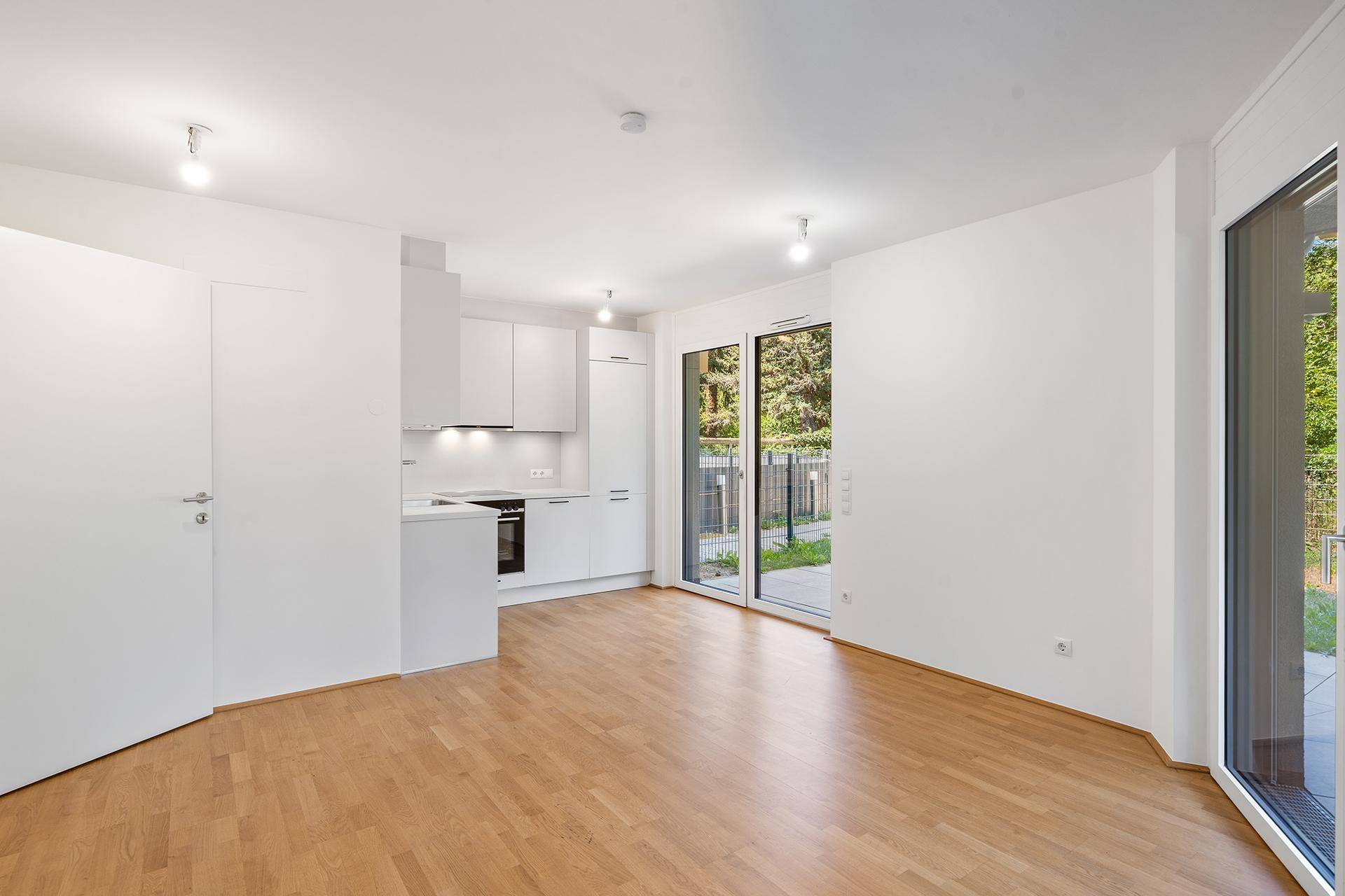 Heller offener Wohn- und Essbereich mit integrierter Küche und Zugang zur Terrasse.